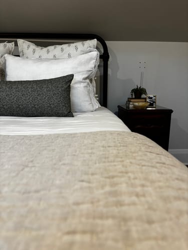 Close-up of a customer's Leighton in Green floral pillow on a bed with white and patterned pillows.