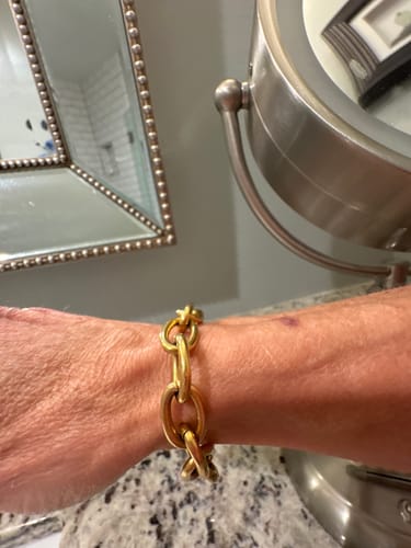 Close-up of a reviewer wearing the chunky, gold J'adore Chunky Bracelet on their wrist.