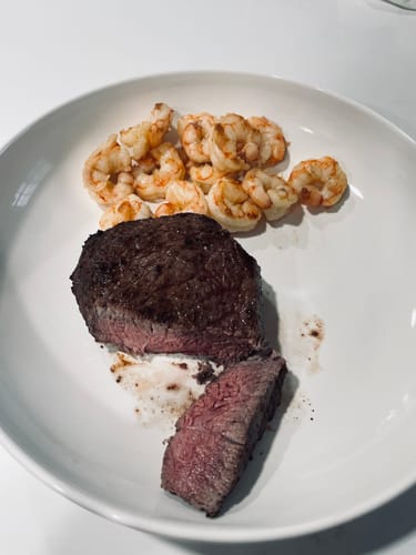 Customer's seared USDA Prime Top Sirloin, sliced on a plate to show the tender pink center.
