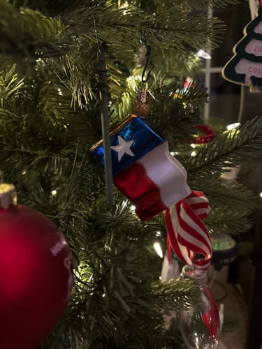 Customer's Texas State Flag Ornament hanging on a lit Christmas tree.