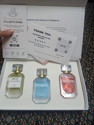 Reviewer's open box showing the OUD Supreme BUNDLE, containing three different colored perfume bottles.