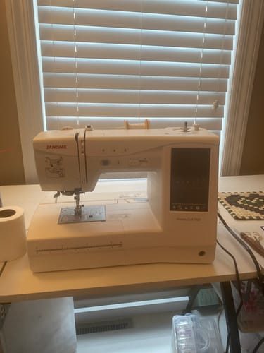 Customer's white Janome Memory Craft 1000 sewing machine sitting on a desk.