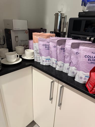 Customer's stock of several Collagen Renew™ pouches lined up neatly on a black kitchen counter.