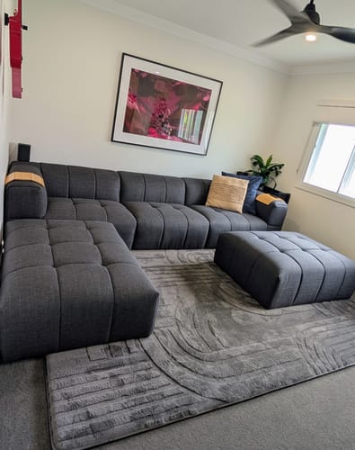 Customer's charcoal Mellow Mat with a carved 3D pattern in a modern living room with a sectional sofa.