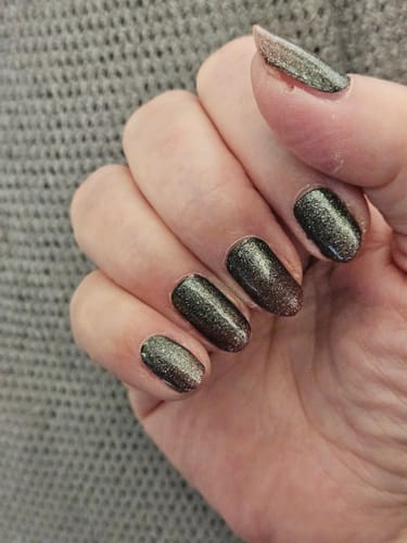 Hand einer Kundin, die die dunklen, glitzernden Nagelfolien Scarlet Ombré Cat Eye trägt.
