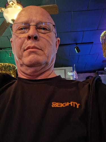 Close-up of a reviewer wearing the black 80Eighty DCG84 shirt with its orange chest logo.