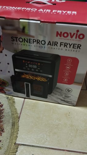 Recenzent prezentând ambalajul produsului Air Fryer Novio StonePro.