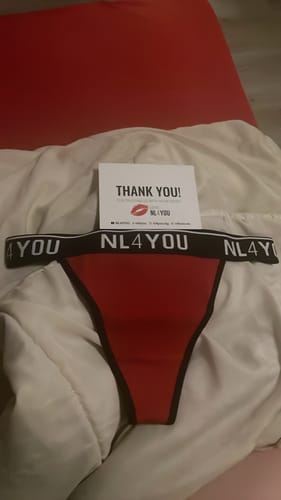 Customer's red thong underwear with a black NL4YOU branded waistband, laid out on a bed with a thank you card.