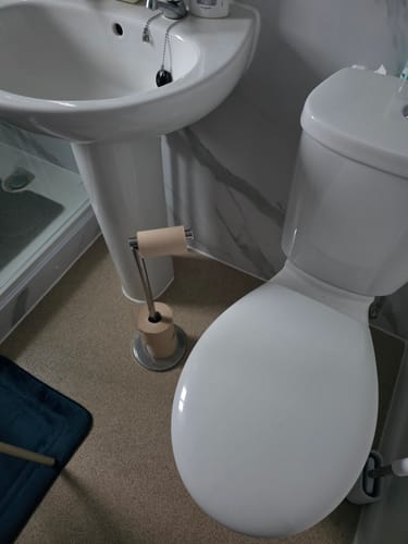 Customer's Unbleached Bamboo Toilet Paper on a freestanding holder in a bathroom next to a toilet.