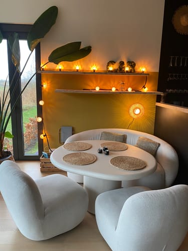 Klant toont de ingeschakelde Kalimantan wandlamp die een warm, stralend effect geeft op een gele muur in de eetkamer.