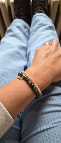 Reviewer wearing the light pink Sunstone Accent Bracelet stacked with a dark green beaded bracelet.
