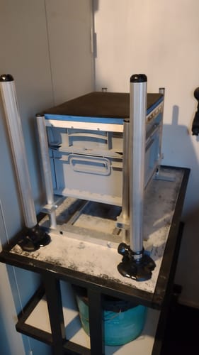 Beoordelaar toont vier zilveren 36mm Seatbox poten gemonteerd op een zelfgebouwde viskist.