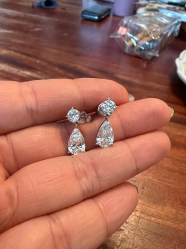 Customer holding the sparkling M & Co. Lab Grown Diamond Round & Pear Drop Earrings in their hand.
