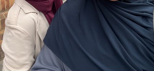 Reviewer wearing a dark navy Premium Jersey Hijab draped over their head and shoulders, standing next to another person.