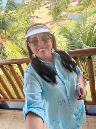 Cliente sorrindo em uma selfie na varanda, usando os Óculos Marsala.