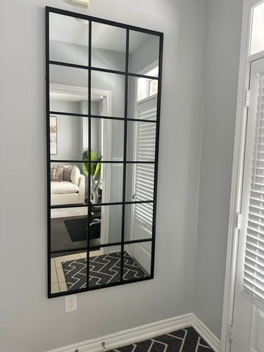 Customer's Modern Black Grid Wall Mirror mounted vertically on a light gray wall in an entryway.
