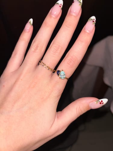 Customer wearing the Leesha Birthstone Ring on their finger, showing the two pear-cut blue stones.