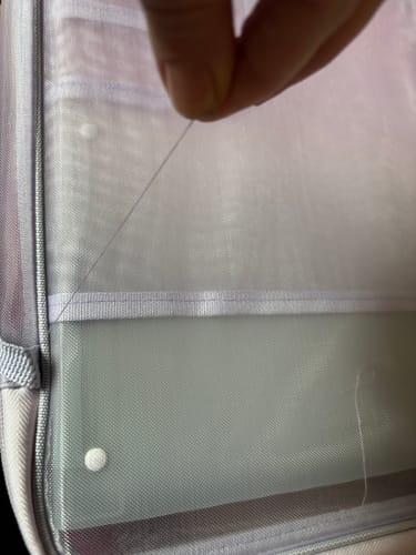 Customer's hand holding a loose thread on the mesh of the violet ClearView Study Organizer.