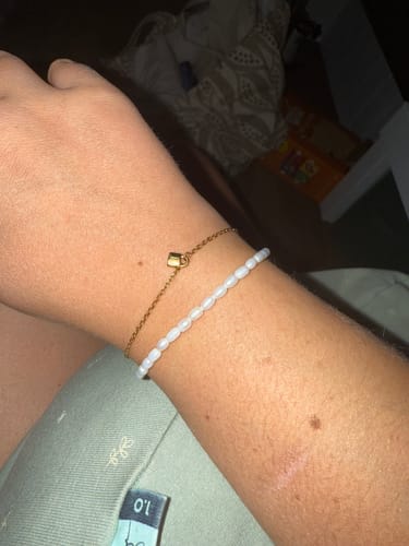 Reviewer wearing the gold Mini Padlock Initial Letter Bracelet on their wrist, paired with a dainty beaded bracelet.