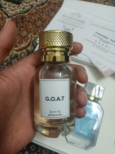 Customer holding a fragrance bottle from the OUD Supreme Bundle, showing its clear glass body and textured gold cap.