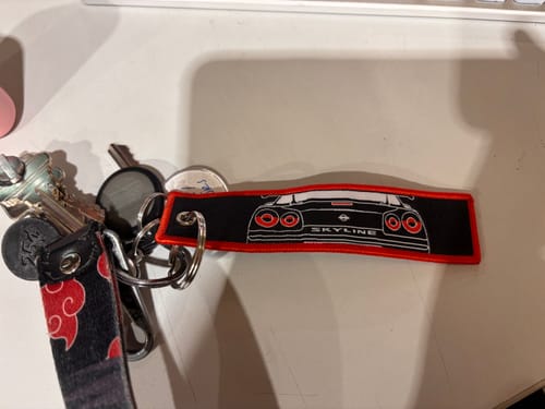 Customer's black and red SKYLINE JET TAG with an embroidered car design, attached to a set of keys.