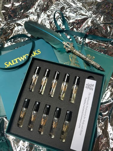 Customer's Discovery Set with ten perfume samples displayed in an open teal box, styled with a quill pen.