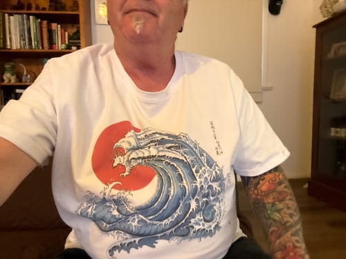 Customer wearing a white t-shirt with a large graphic of a blue wave in front of a red sun.