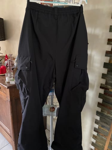 Customer's black baggy snow pants hanging on a hanger, showing the loose fit and large cargo pockets.