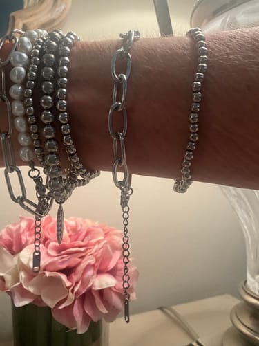 Reviewer's wrist showing the long extender chain of the Tulum Chunky Paperclip Bracelet dangling among a stack of other bracelets.
