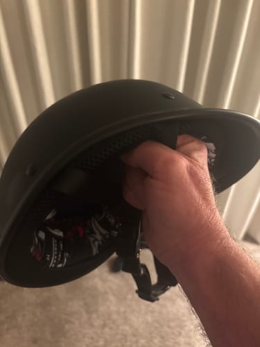 A reviewer's hand holding the Polo Switchback helmet, showing the padded interior and straps.