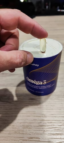 Avis d'un client montrant une gélule claire d'Oméga 3 EPAX® tenue au-dessus de son pot bleu et blanc.
