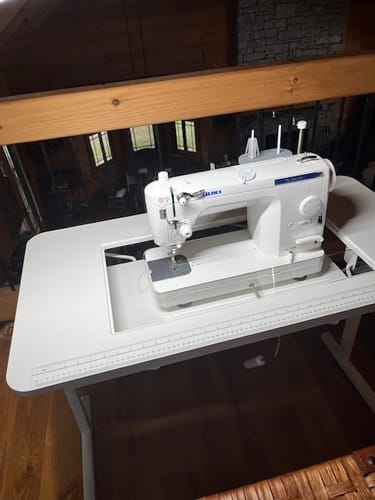 Reviewer's white sewing machine in a portable table, showing the cutout where the Sew Steady Cabinet Insert fits.