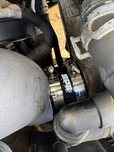Close-up of the customer's SPE Motorsport Cold Side Pipe, showing the black and silver coupler with the SPE logo installed in an engine.