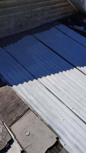 Cliente muestra un techo corrugado a medio pintar con el Sellador de Techos Lanco Coolguard.