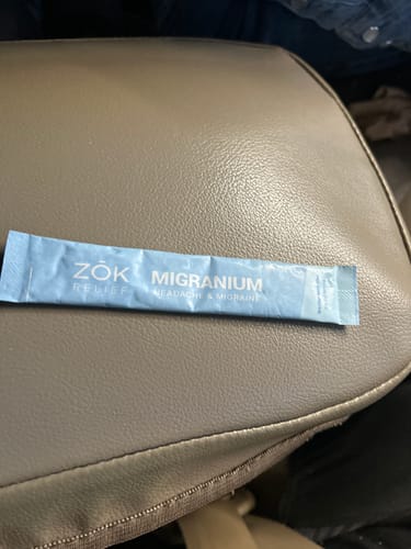 A reviewer's single light blue Migranium packet resting on what appears to be a car seat.