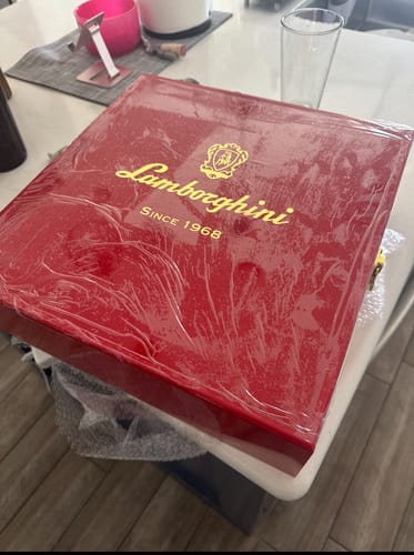 Customer's red Lamborghini LUXE Red Collection gift set box, sealed in plastic wrap on a table.