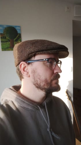 Reviewer in profile, wearing the brown Vintage Cap Ear Flap Tweed indoors.