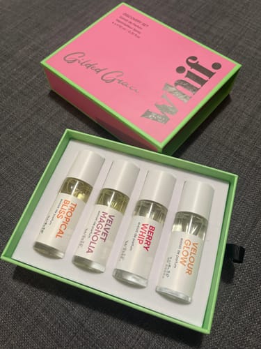 Customer's open Discovery Set showing the four included perfume bottles in their green box, with the pink lid next to it.