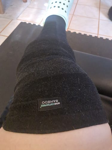 A customer's personal view of the black Premium Bamboo Knee Sleeve worn on their leg over a compression sock.