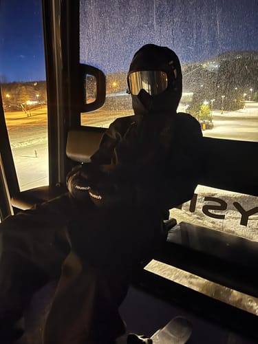 Reviewer sitting in a ski lift at night wearing the dark, baggy Snow Pants.