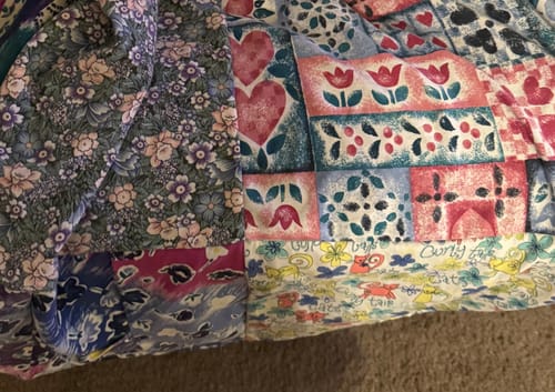 Customer's close-up of a Premium T Shirt Quilt, showing the patchwork design made of colorful patterned fabrics.