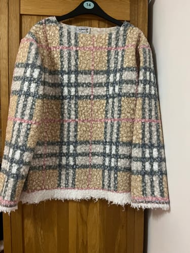 Customer's warm winter top made from the checkered Heritage Check Boucle Fabric, hanging on a door.
