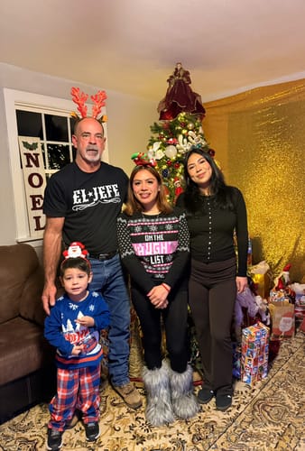 Customer wearing the black El Jefe T-Shirt while posing with family in front of a Christmas tree.