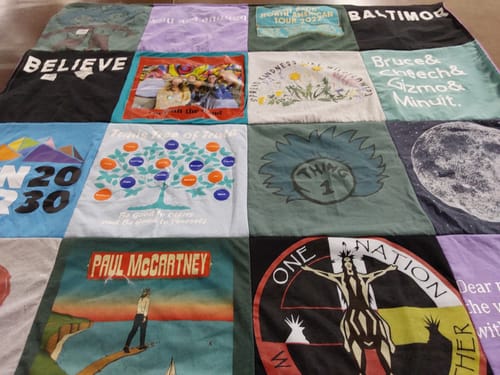 Customer's colorful Premium T Shirt Quilt spread out, showing squares made from various personal t-shirts.