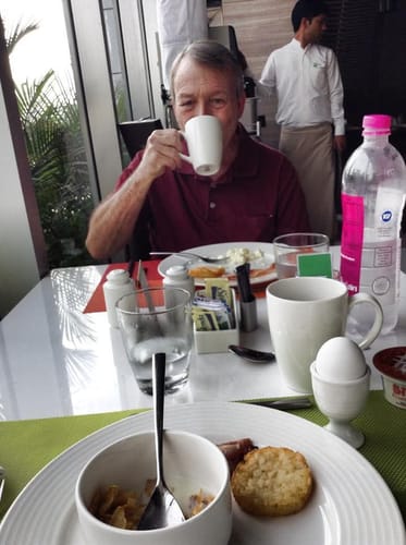 Reviewer sips Costa Rican Dark Roast Coffee from a white mug at breakfast.