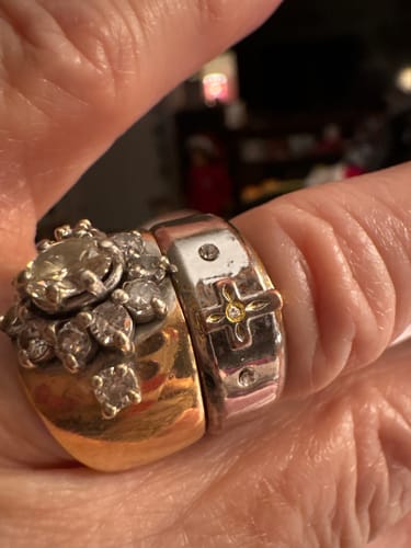 Close-up of the reviewer's two-tone gold cross ring worn on their finger next to a diamond wedding ring.