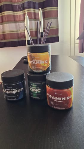Reviewer's Complex Liposomal Vitamin C supplement shown on a table with other supplements from the same brand.