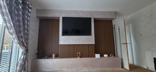 Customer's brown Acoustic Slatted Wall Panels installed as a feature wall behind a television in a living room.