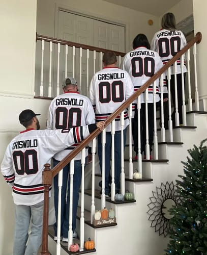 Reviewer's family members seen from behind on a staircase, all wearing matching white 'Griswold' 00 hockey jerseys.