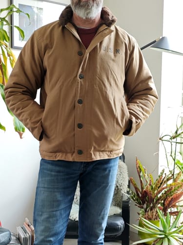 Reviewer wearing the tan 1940s US Navy N-1 Deck Jacket, showing the fit with a dark furry collar and 'U.S.N.' on the chest.